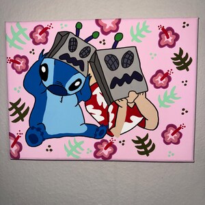May include: A hand-painted canvas featuring the character Stitch from Lilo & Stitch, along with two characters wearing gray box-like masks. The background is pink, decorated with hibiscus flowers and green leaves. The artwork is a cartoon style.