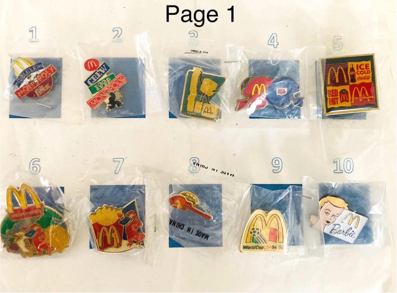 Puede incluir: Una colecci&oacute;n de pines de McDonald's, cada uno en una bolsa de pl&aacute;stico. Los pines presentan varios dise&ntilde;os, incluyendo Monopoly, logotipos de tripulaci&oacute;n y el logotipo de McDonald's. Algunos pines tienen texto como "Ice Cold" y "Barbie".