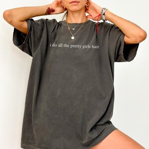 Może przedstawiać: Ciemnoszara koszulka z białym napisem "i do all the pretty girls hair". Koszulka ma kr&oacute;tkie rękawy i luźny kr&oacute;j. Koszulka wykonana jest z miękkiego, wygodnego materiału.