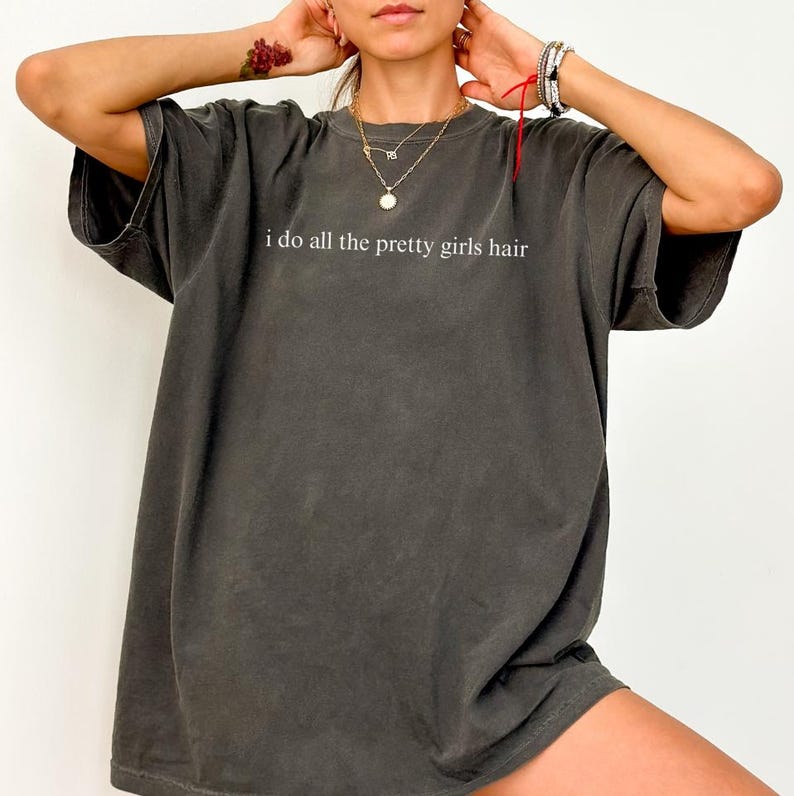 Może przedstawiać: Ciemnoszara koszulka z białym napisem "i do all the pretty girls hair". Koszulka ma kr&oacute;tkie rękawy i luźny kr&oacute;j. Koszulka wykonana jest z miękkiego, wygodnego materiału.