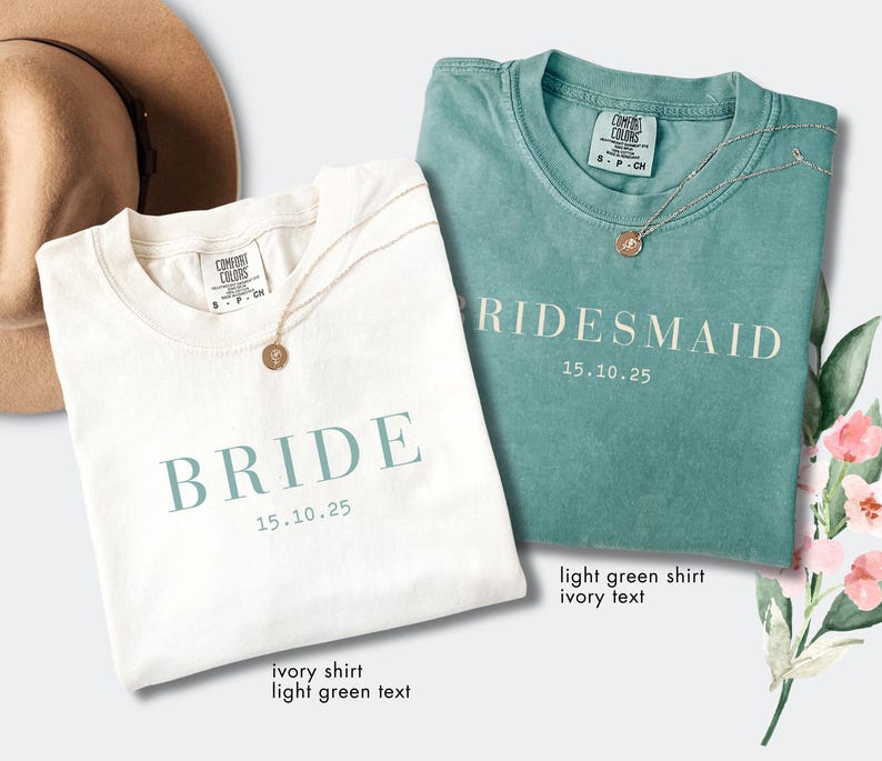 May include: Two t-shirts, one ivory and one light green, are displayed. The ivory shirt has "BRIDE" and "15.10.25" in light green text. The light green shirt has "RIDESMAID" and "15.10.25" in ivory text. Each shirt has a gold necklace.