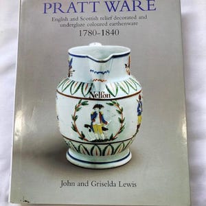 Puede incluir: Un libro titulado "PRATT WARE" que presenta cerámica inglesa y escocesa decorada en relieve y coloreada bajo vidriado de 1780-1840. La portada muestra una jarra de cerámica blanca y azul con figuras decorativas y el nombre "Nelfon".