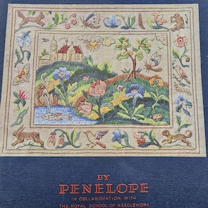 May include: A framed needlepoint tapestry with a detailed landscape scene. The artwork depicts a castle, flowers, butterflies, and animals. The text "BY PENELOPE" is visible at the bottom, indicating the artist or brand.