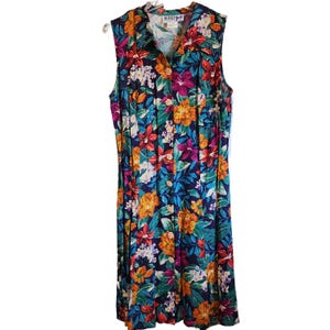 May include: Sleeveless floral print dress with a button-down front. The dress features a vibrant pattern of orange, purple, white, and blue flowers on a dark blue background. The dress is hanging on a white hanger.
