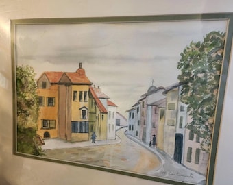 May include: Watercolor painting of a European street scene with buildings in shades of yellow, orange, and blue. A winding road leads into the distance, with figures of people walking. The artwork is framed.