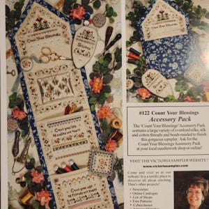 May include: An accessory pack for needlework, featuring a cream-colored organizer with pockets, floral embroidery, and the text "Count Your Blessings." Includes scissors, pins, and spools of thread. The pack is surrounded by floral accents.