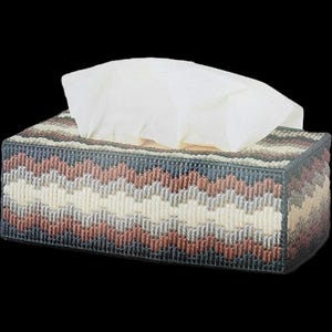 May include: Rectangular tissue box cover with a woven chevron pattern in shades of blue, brown, cream, and gray. White tissues are visible at the top. The cover is designed to hold a standard tissue box.
