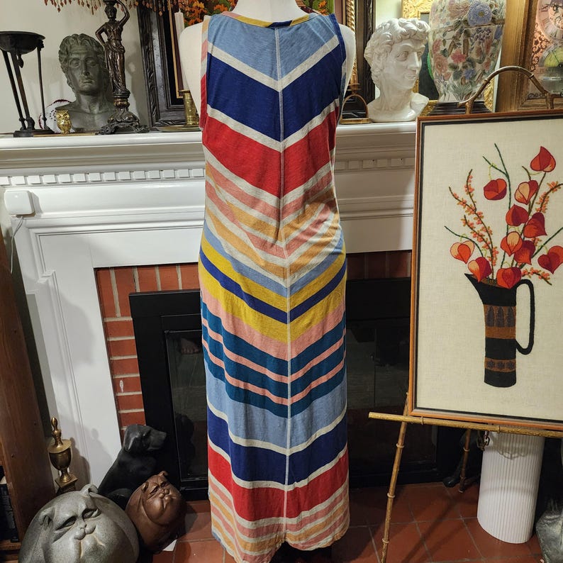 Puede incluir: Vestido largo sin mangas con un patr&oacute;n de chevron y rayas. El vestido presenta una paleta de colores rojo, azul, amarillo y rosa. El vestido se exhibe en un maniqu&iacute;.