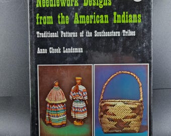 May include: A vintage book titled "Needlework Designs from the American Indians" by Anne Cheek Landsman. The cover features images of traditional Native American patterns and figures, including a woven basket and two figures in traditional clothing.