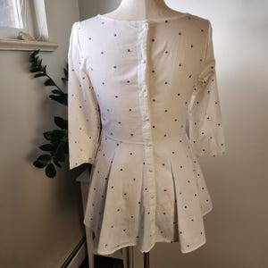 May include: White dress with a blue polka dot pattern and a button-up back.