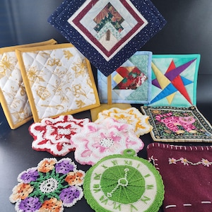 May include: A collection of handmade quilted and crocheted pot holders and trivets in various shapes and designs. Includes square, round, and flower-shaped items with floral, geometric, and abstract patterns. Colors include white, yellow, red, purple, and green.