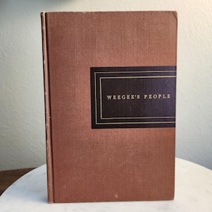 May include: A brown book with a gold title on a black background that reads "Weegee's People".