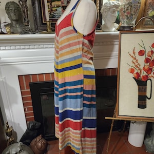 Puede incluir: Un vestido a rayas de colores con cuello en V y tirantes finos. El vestido presenta rayas horizontales en rojo, amarillo, azul y gris. El vestido se exhibe en un maniqu&iacute;.