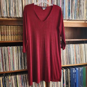 May include: A long-sleeved, burgundy v-neck top with a slightly loose fit. The top is made of a soft, textured fabric.