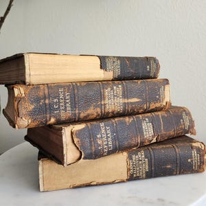 May include: A stack of five vintage leather-bound books with gold lettering. The books are titled "I.C.S. Reference Library" and feature various subjects like "Historic Ornament", "Carpet, Wallpaper, Bookcover, Linoleum and Architectural Design", and "Perspective, Aerial, and-Ink Rendering, Drawing from Nature Cast and the Figure".