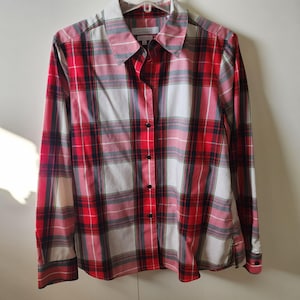 May include: A red, white, and black plaid button-down shirt with long sleeves. The shirt has a collared neckline and black buttons. The brand name is visible on the label.