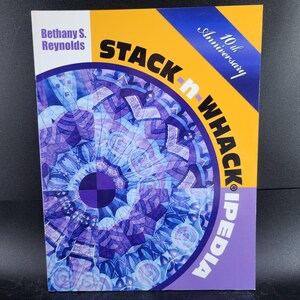 May include: A book titled "STACK n WHACK iPEDIA" by Bethany S. Reynolds. The cover features a geometric design in shades of blue and purple, with a yellow and purple background. The book celebrates its 10th anniversary.
