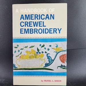 May include: A Handbook of American Crewel Embroidery book. The cover features the title in white and blue, with a decorative border and illustrations of fruit and a bird. The author's name, Muriel L. Baker, is at the bottom.