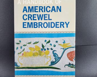 May include: A Handbook of American Crewel Embroidery book. The cover features the title in white and blue, with a decorative border and illustrations of fruit and a bird. The author's name, Muriel L. Baker, is at the bottom.