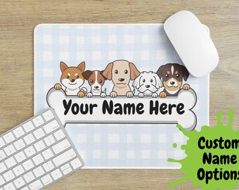 Puede incluir: Alfombrilla de ratón azul claro con estampado de cuadros y un diseño en forma de hueso con cinco perros de dibujos animados. El texto "Your Name Here" se muestra en el hueso. También se ven un ratón y un teclado blancos.