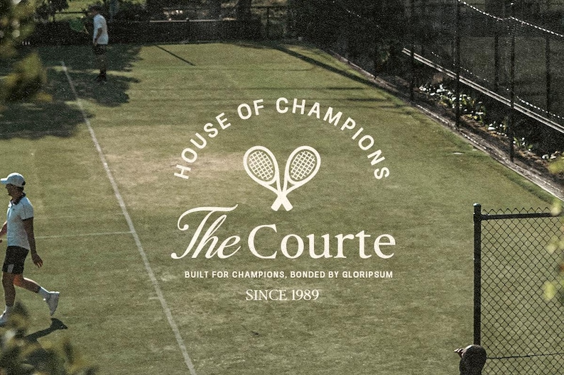 May include: An outdoor tennis court with the text "HOUSE OF CHAMPIONS" and "The Courte" in white. Two tennis rackets are crossed above the text. The text "SINCE 1989" is also visible. Two people are on the court.