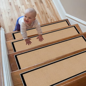 Può includere: Battiscopa per scale beige con bordatura nera, progettati per evitare scivolamenti. Un bambino piccolo sale le scale.