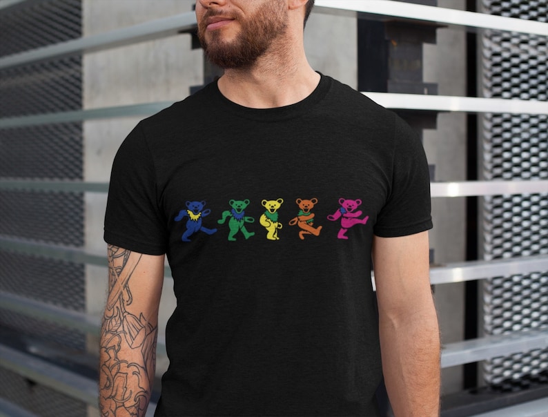 May include: A black t-shirt with a graphic of five dancing bears in rainbow colors. The bears are wearing hats and have different expressions.