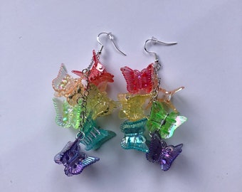 May include: Rainbow butterfly dangle earrings with a silver chain and hook. The butterflies are iridescent and have a layered look.