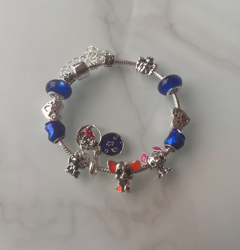 May include: A silver charm bracelet with blue and silver beads and charms, including a dog, a heart, and a star.