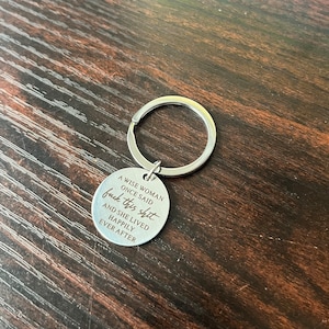 Może przedstawiać: Srebrny brelok do kluczy z okrągłą zawieszką. Na zawieszce wygrawerowano napis: "A WISE WOMAN ONCE SAID fuck this shit. AND SHE LIVED HAPPILY EVER AFTER."