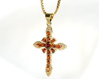 Op de afbeelding: Een gouden ketting met een kruis hanger versierd met bruine en heldere edelstenen.