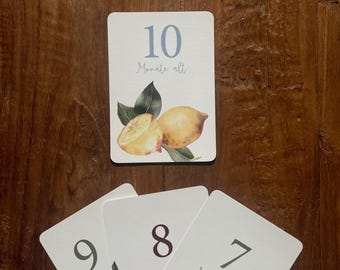 May include: A set of three cards with numbers 7, 8, and 9. The cards are white with a light blue, dark red, and green number on each. The cards also have the text "Monate alt" on them. The cards are decorated with watercolor illustrations of lemons and leaves.