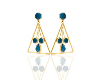 Könnte beinhalten: Ein Paar goldfarbene Ohrringe mit dreieckigem Design. Jeder Ohrring hat einen großen, runden blauen Edelstein oben und drei kleinere blaue Edelsteine, die darunter hängen. Der untere Edelstein ist tropfenförmig. Die Ohrringe werden auf weißem Hintergrund präsentiert.
