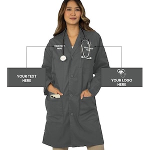 May include: A dark gray lab coat featuring a button-down front, long sleeves, and two large front pockets. The chest area includes white text reading YOUR TEXT HERE and YOUR LOGO HERE with a stethoscope graphic. A stethoscope rests around the neck.