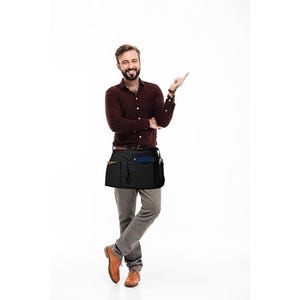 May include: A black waist apron featuring multiple storage pockets, worn over a long-sleeved maroon button-down shirt and grey trousers. The apron is designed with a functional layout for carrying tools or supplies, secured around the waist.