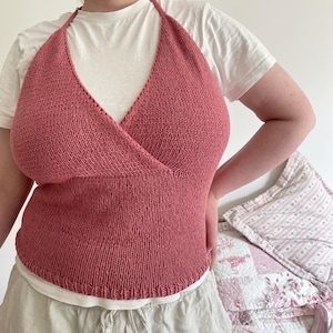 May include: A pink knitted halter top with a criss-cross front.