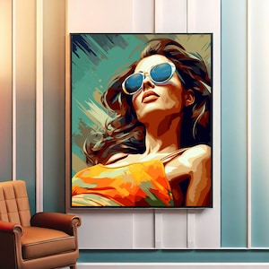 May include: A framed art print of a woman wearing sunglasses, looking upwards. The artwork features a vibrant color palette of orange, blue, and brown. The woman's hair is flowing, and she is wearing an orange top.