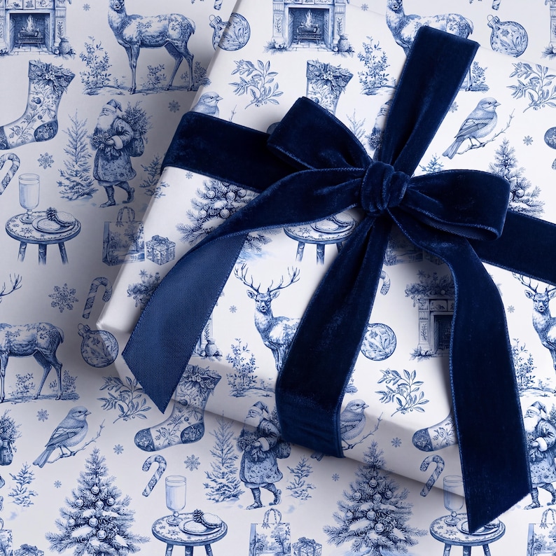 Puede incluir: Una caja de regalo rectangular envuelta en papel blanco con un patr&oacute;n navide&ntilde;o azul repetitivo de estilo toile que muestra ciervos, Pap&aacute; Noel, p&aacute;jaros, calcetines y &aacute;rboles, atada con un lazo grande de cinta de terciopelo azul marino oscuro.