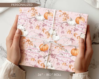 May include: Pink wrapping paper with a floral and pumpkin design. The paper is tied with a white ribbon and features the text "Happy Birthday Olivia". The roll is 36 inches to 180 inches.
