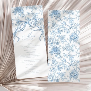 Op de afbeelding: Twee elegante menukaarten met een blauw bloemmotief op een witte achtergrond. De linkerkaart bevat een menu met koppen voor salade, hoofdgerecht en dessert. De rechterkaart toont een bijpassend bloemmotief. De menutekst is in een sierlijk handschrift.