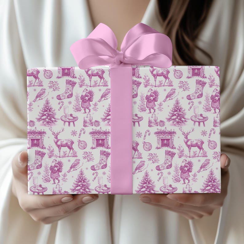 Puede incluir: Una caja de regalo rectangular envuelta en papel blanco con un patr&oacute;n de toile magenta repetitivo que presenta ilustraciones de Santa Claus, renos, &aacute;rboles de Navidad, calcetines y chimeneas, terminada con un lazo de cinta de sat&eacute;n magenta.