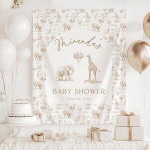 May include: A rectangular fabric backdrop featuring a beige safari animal pattern with elephants and giraffes. The center displays the text "Miranda's BABY SHOWER June 20, 2025" with illustrations of an elephant, a giraffe, and balloons.