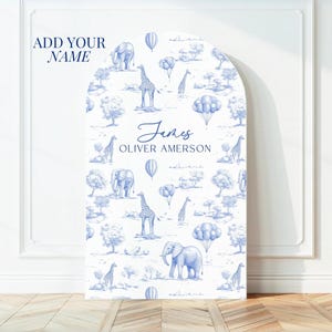 Op de afbeelding: Een blauwe en witte boog achtergrond met een safari thema. De achtergrond heeft olifanten, giraffen, luchtballonnen en bomen. De tekst "James Oliver Amerson" is op de achtergrond gedrukt.
