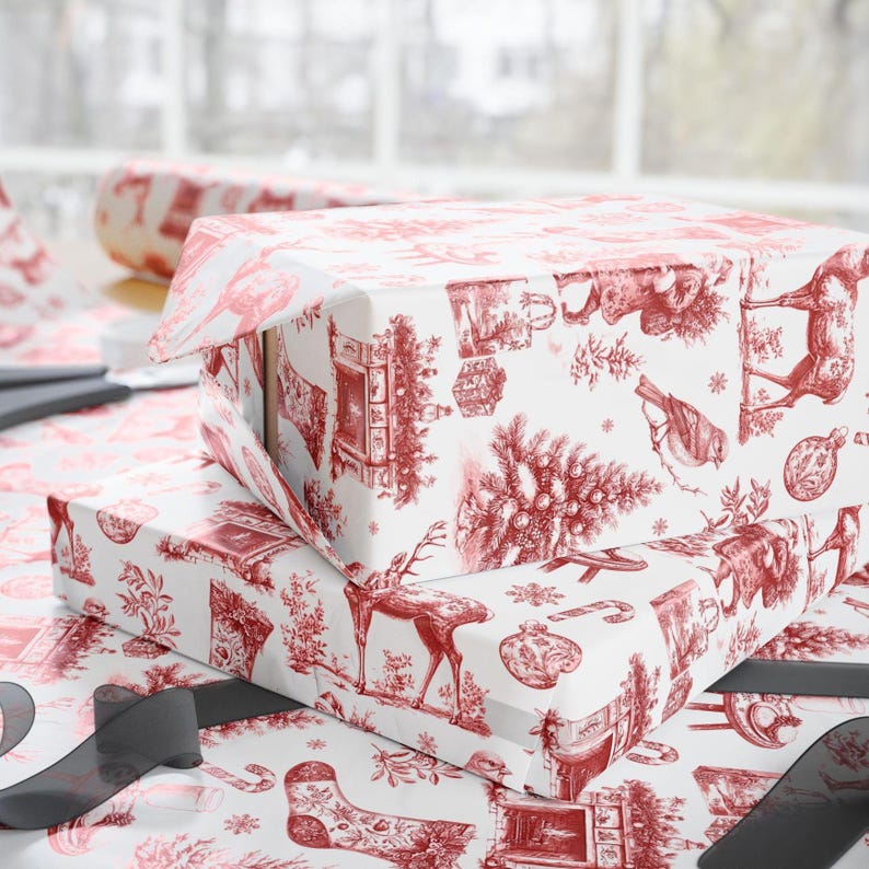 Puede incluir: Dos cajas de regalo rectangulares envueltas en papel blanco con un estampado rojo estilo toile de motivos navide&ntilde;os que incluyen ciervos, &aacute;rboles de Navidad, calcetines, adornos y chimeneas. Las cajas est&aacute;n apiladas sobre una superficie a juego.