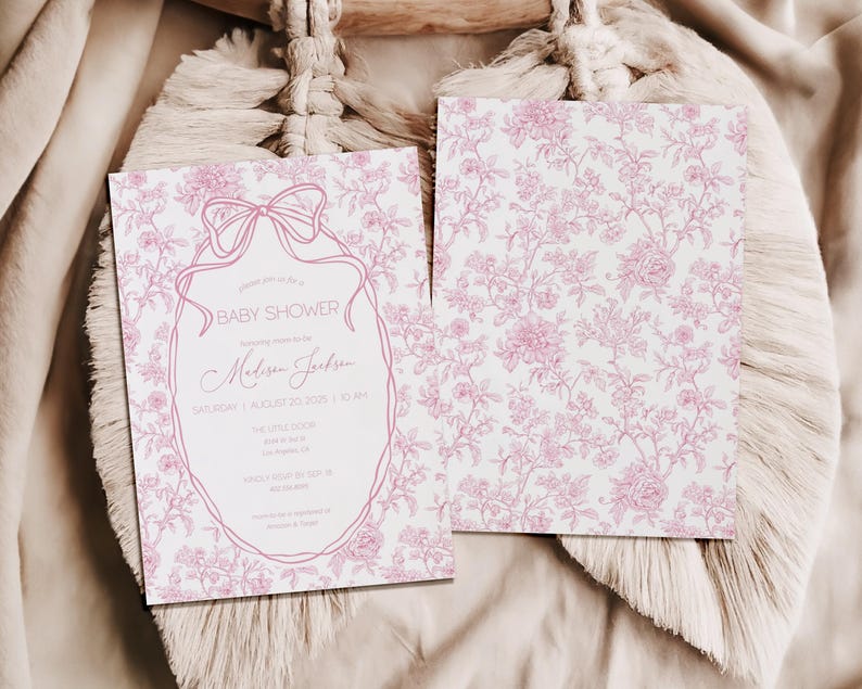 May include: Baby shower invitation with a pink floral design and text. The invitation features a bow and an oval frame with the words "Baby Shower" and event details. The back of the invitation has a pink floral pattern.
