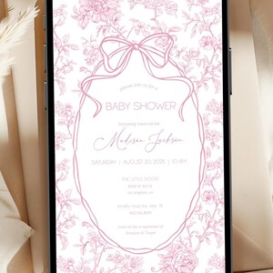 May include: A baby shower invitation displayed on a smartphone. The invitation features a pink floral design with a bow and text that reads "Baby Shower" and details for Madison Jackson's shower on August 20, 2025.