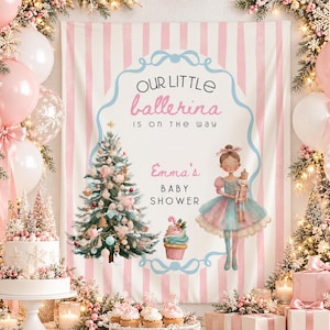 May include: A rectangular backdrop featuring pink and white vertical stripes, a central blue frame, and text reading Our Little Ballerina Is On The Way and Emma's Baby Shower. It includes illustrations of a Christmas tree, a cupcake, and a ballerina.