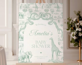 May include: A baby shower sign on an easel. The sign features a light green and white design with giraffes, elephants, and hot air balloons. The text reads "Welcome to Amelia's BABY SHOWER".