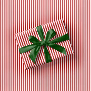 Puede incluir: Una caja de regalo rectangular envuelta en papel con finas rayas verticales rojas y blancas. La caja est&aacute; atada con una cinta de sat&eacute;n verde oscuro que forma un lazo grande de m&uacute;ltiples bucles centrado en la superficie superior.