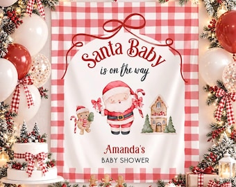 May include: A rectangular backdrop featuring a red and white buffalo check border, the text Santa Baby is on the way, a watercolor illustration of Santa Claus, a gingerbread person, a gingerbread house, and the text Amanda's BABY SHOWER.